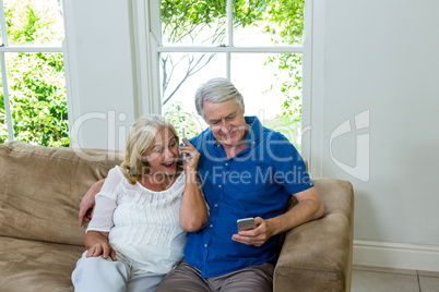 Surprised senior couple looking at mobile phone at home