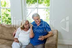 Surprised senior couple looking at mobile phone at home