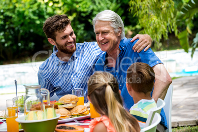 Father and son with children at dinning table in lawn