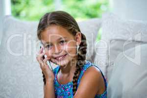 Smiling girl talking on mobile phone at home