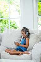 Girl listening music while using mobile phone at home