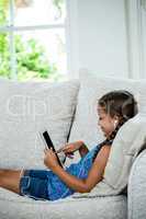 Girl using digital tablet while relaxing on sofa