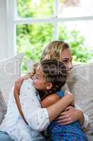 Happy mother and daughter embracing on sofa