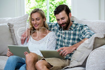 Happy couple using digital tablet on sofa