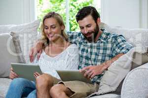 Happy couple using digital tablet on sofa