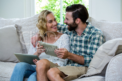 Couple looking at each other while holding digital tablets