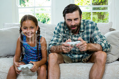 Portrait of father and daughter playing video game at home