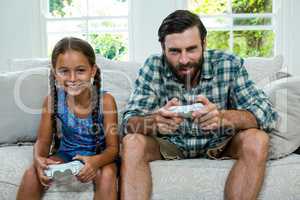 Portrait of father and daughter playing video game at home