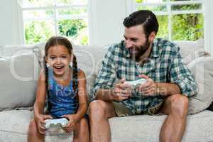Happy father looking at daughter while playing video game at hom