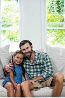 Portrait of cheerful father with daughter on sofa