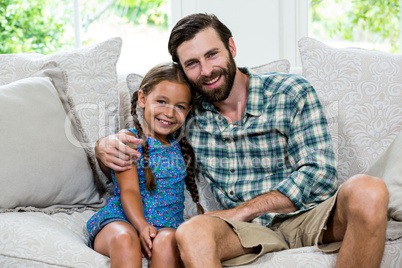 Portrait of happy father with daughter on sofa