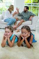 Upset children lying against parents fighting at home