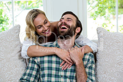 Young woman embracing man from behind against window