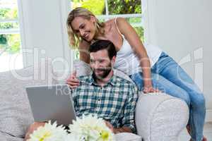 Woman leaning on man with laptop on sofa