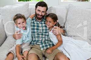 Cheerful father with son and daughter on sofa