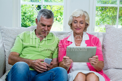 Senior couple with digital tablet and mobile phone at home