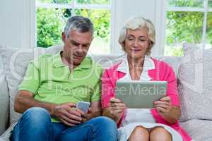 Senior couple with digital tablet and mobile phone at home