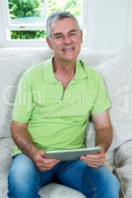 Portrait of senior man holding digital tablet at home