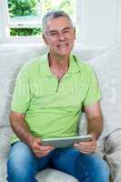 Portrait of senior man holding digital tablet at home