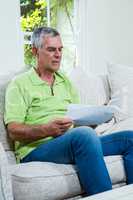 Worried senior man holding documents at home