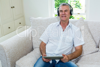 Cheerful senior man listening music at home