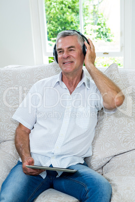 Happy senior man listening music in sitting room
