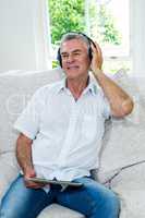 Happy senior man listening music in sitting room