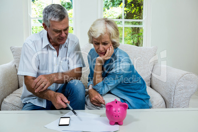 Senior man discussing with wife regarding savings on sofa