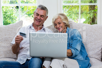 Senior couple shopping online using laptop at living room