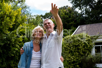 Senior man pointing while standing with wife in back yard