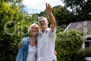 Senior man pointing while standing with wife in back yard