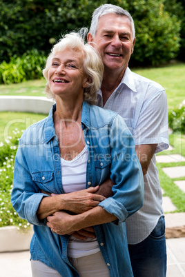 Portrait of senior man embracing from behind in back yard