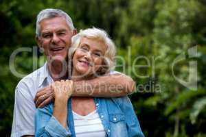 Senior man embracing wife from behind in back yard
