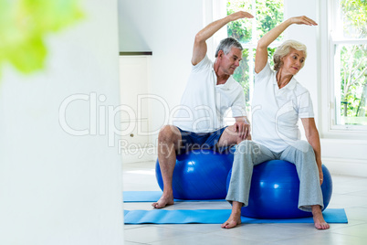 Active senior couple doing aerobics on ball