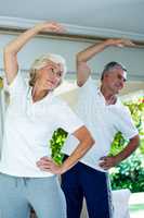 Senior couple bending while doing aerobics
