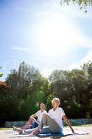Senior couple exercising at poolside against sky