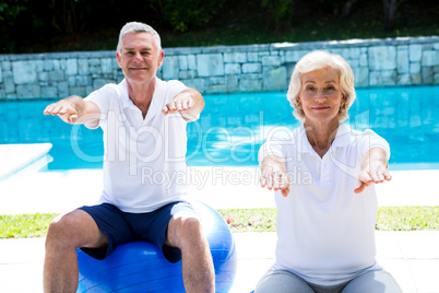 Portrait of senior couple doing aerobics at poolside