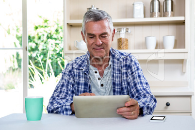 Senior man using digital tablet against shelves