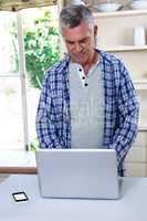 Senior man using laptop in kitchen