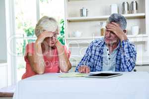 Worried senior couple with documents at table