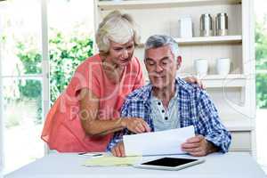Senior woman discussing with husband on documents at table