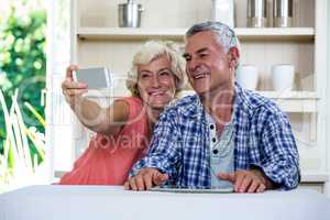 Senior couple taking selfie through mobile phone while sitting i