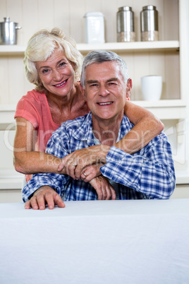 Happy senior couple hugging in kitchen at home