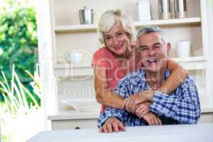 Smiling senior couple hugging in kitchen at home