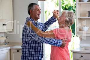 Happy senior couple dancing in kitchen