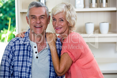 Smiling senior man with woman in kitchen at home