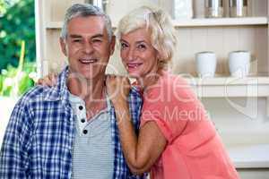 Smiling senior man with woman in kitchen at home