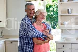 Smiling couple embracing in kitchen at home