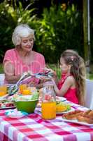 Grandmother serving food to granddaughter