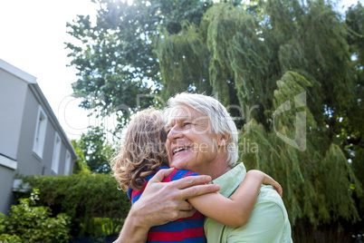 Grandfather hugging grandson at yard